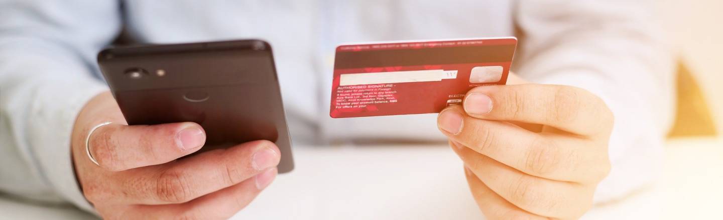 En personen håller ett kreditkort och en telefon